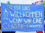 Banner: GE ist uns willkommen, wenn wir eine Chance bekommen